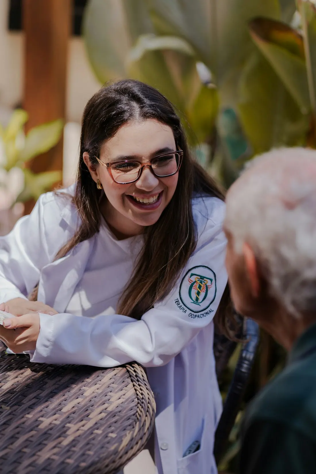 Uma terapeuta sorridente fala com um paciente mais velho